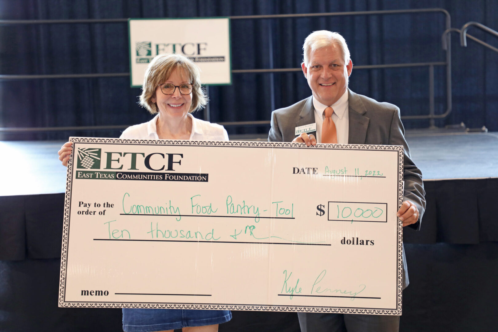 A man and woman holding up a large check.